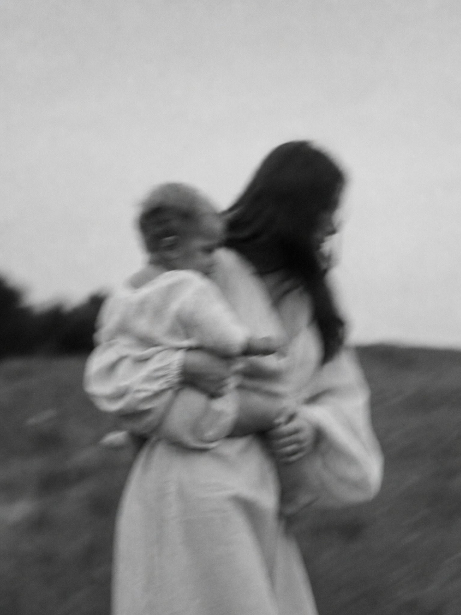 A softly blurred black and white portrait of a woman holding a child